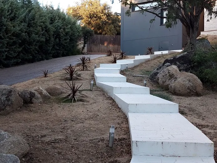 Murete blanco y camino de losas en un jardín en obras